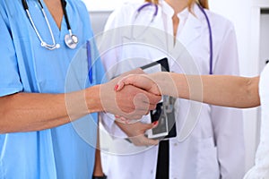 Male doctor and female patient shaking hands. Partnership, trust and medical ethics concept