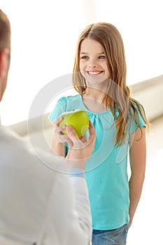 Male doctor giving an apple to smiling little girl