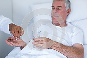 Male doctor giving pill to senior man