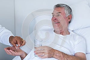 Male doctor giving pill to senior man