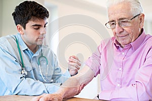 Male Doctor Giving Senior Man Vaccine Injection In Arm With Syringe