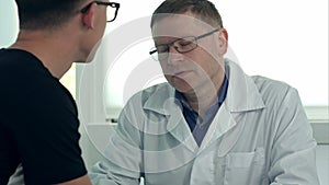 Male doctor in glasses consulting male patient