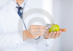 Male doctor with green apple and stethoscope