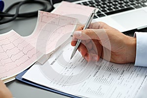 Male doctor hands with cardiogram chart on clipboard pad