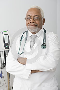 Male Doctor With Hands Folded Standing At Clinic