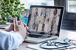 Male doctor having video conference on laptop with his colleagues at home