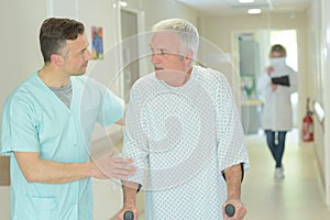 Male doctor helping older patient with crutches