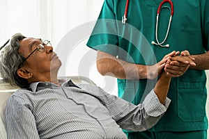 Male doctor holding hand of senior adult patient.