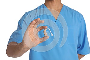 Male doctor holding hearing aid on white background, closeup.