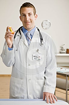 Male doctor holding out medication bottle