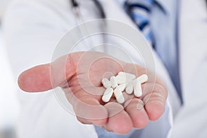 Male doctor holding pills in hand