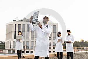 Male doctor holding x-ray scan of patient during break outdoors hospital.