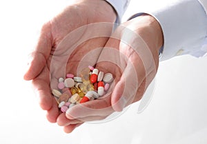 Male doctor holding a stack of many different pills