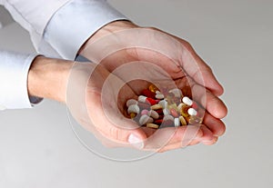 Male doctor holding a stack of many different pills