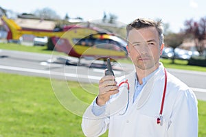 Male doctor holding talkie walkie near rescue helicopter