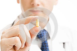 Male doctor holdling one pill in hand - studio shot