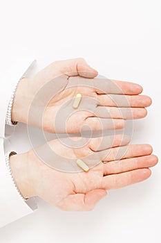 Male doctor holdling one pill over each of his palms - studio shot