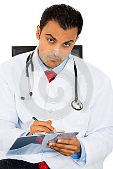 Male doctor in lab coat holding reading Patients Chart while sitting on a chair