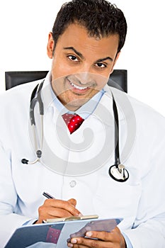 Male doctor in lab coat holding reading Patients Chart while sitting on a chair