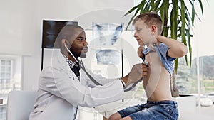 Male doctor listening the heartbeat of little boy using stethoscope.