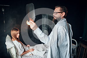 Male doctor looking at x-ray picture of sick woman