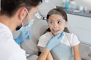 Male doctor looking at small client sitting in the dental chair