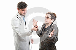 Male doctor making cash gesture to female senior patient