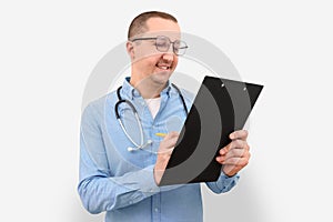 Male doctor making notes on a clipboard on a gray studio background. Health care and medicine