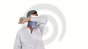 A male doctor in mask hiding his face with arm in isolated solid background. contagious disease public shaming concept