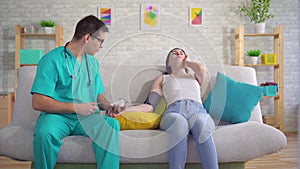 Male doctor measures a young woman`s blood pressure with a tonometer