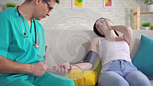 Male doctor measures a young woman`s blood pressure with a tonometer close up