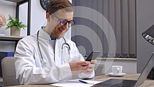 Male doctor medical worker in modern clinic wearing eyeglasses and white coat uniform using cell mobile smartphone apps