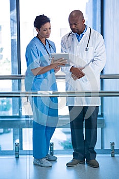 Male doctor and nurse using digital tablet in corridor