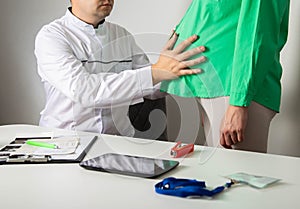 Male doctor obstetrician gynecologist palpates the belly of a pregnant girl. The concept of observing pregnancy by a doctor.