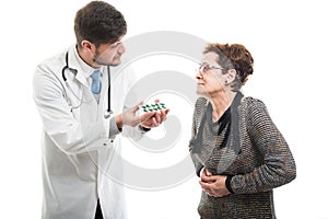 Male doctor offering pills to female senior patient