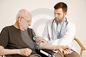 Male doctor and old man on a wheelchair isolated on a white background