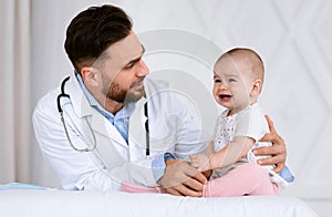 Male Doctor Pediatrician Examining Little Baby Girl In Clinic Indoors