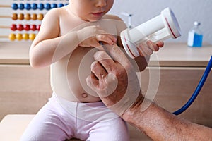 Male doctor pediatrician uses a stethoscope gadget to examine the health of a little patient, baby, little child helps, the