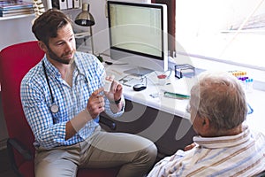 Male doctor prescribing pills to his senior male patient in clinic