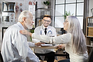 Male doctor providing medical consultation for aged couple