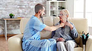 Male doctor putting his stethoscope on and listening old woman heartbeat