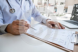 The male doctor sat and checked the patient`s history and used a laptop to record patient information at the hospital. Medical