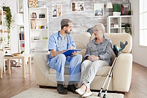 Male doctor with senior woman sitting on couch