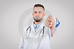 Male doctor showing disapproval with a thumbs-down gesture