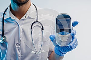 Male doctor showing electronic thermometer in hand