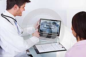 Male Doctor Showing Teeth X-ray To Patient