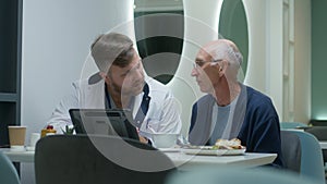 Male doctor shows medical test results to senior patient