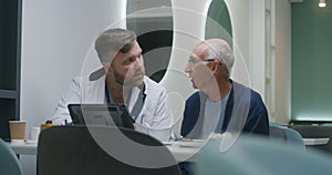 Male doctor shows medical test results to senior patient