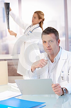 Male doctor sitting at desk doing paperwork