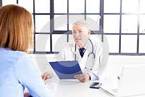 Male doctor sitting at doctor`s office and consulting with her female patient